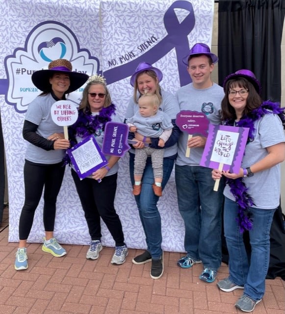 Family Posing For A Photo Dressed In Purple At Nonprofit Event